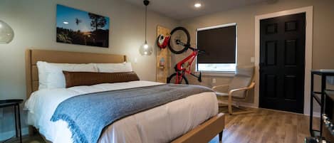 A bedroom with a bed, a bicycle, a window, and a door.