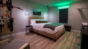 A bedroom with a bed, a bicycle rack, a desk, and a window with a view. - The Bike Inn #4, Centennial Park, Single Room (Bentonville)