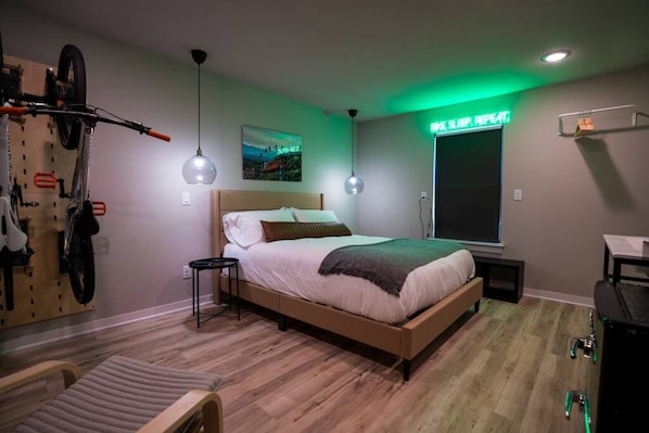 A bedroom with a bed, a bicycle rack, a desk, and a window with a view.