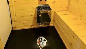 A small, enclosed room with wooden walls and a black floor. There is a stove with a pot on it and a small black object hanging on the wall. - The Bike Inn #4, Centennial Park, Single Room (Bentonville)
