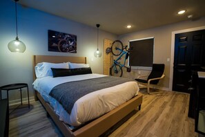 Une chambre à coucher moderne avec un lit en bois, un vélo accroché au mur et un bureau avec une chaise.