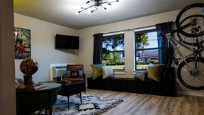 A living room with a sofa, a television, a globe, and a bicycle. - The Bike Inn #8, Boujee Bike Suite (Bentonville)