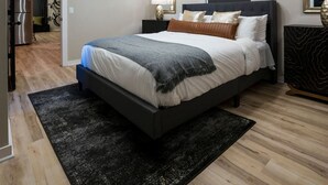 A modern bedroom with a large bed, a flat-screen TV, a mirror, and a bicycle in the background. - The Bike Inn #8, Boujee Bike Suite (Bentonville)