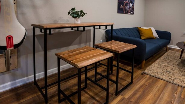 Une pièce avec une table et un banc en bois, un canapé bleu et un petit tapis.