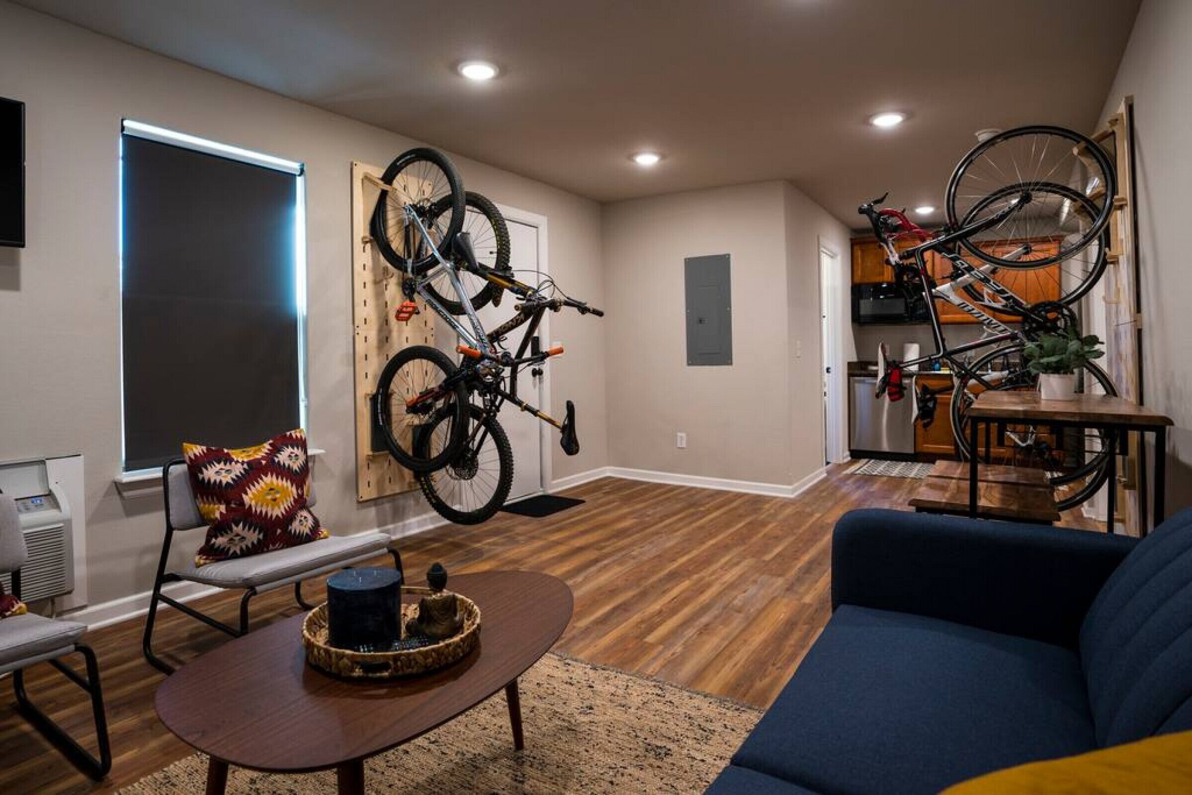 Un salon comprenant un canapé, une table basse et un support à vélos fixé au mur, sur lequel sont accrochés deux vélos.