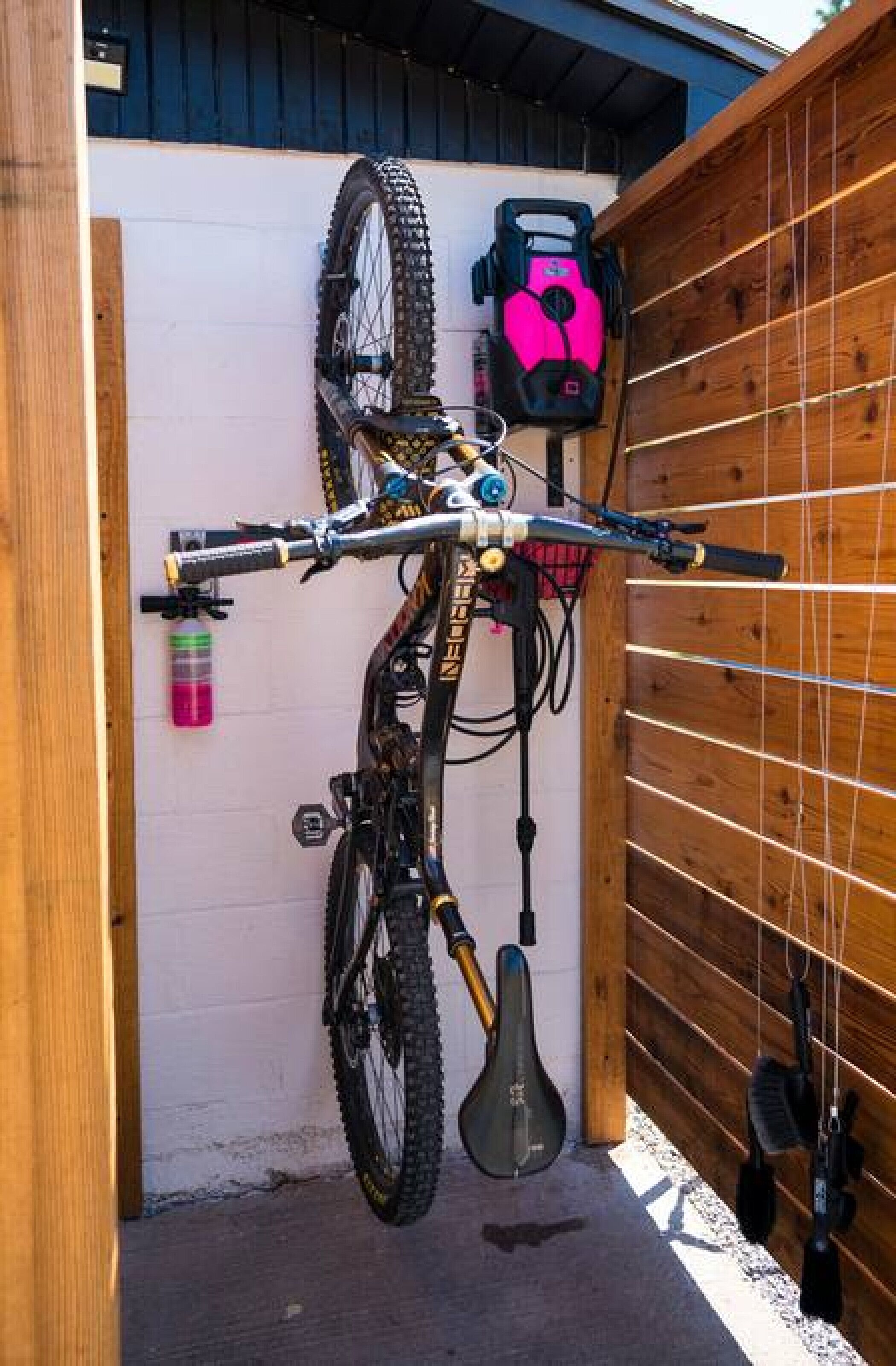 A mountain bike mounted on a wall with a helmet and a water bottle nearby.
