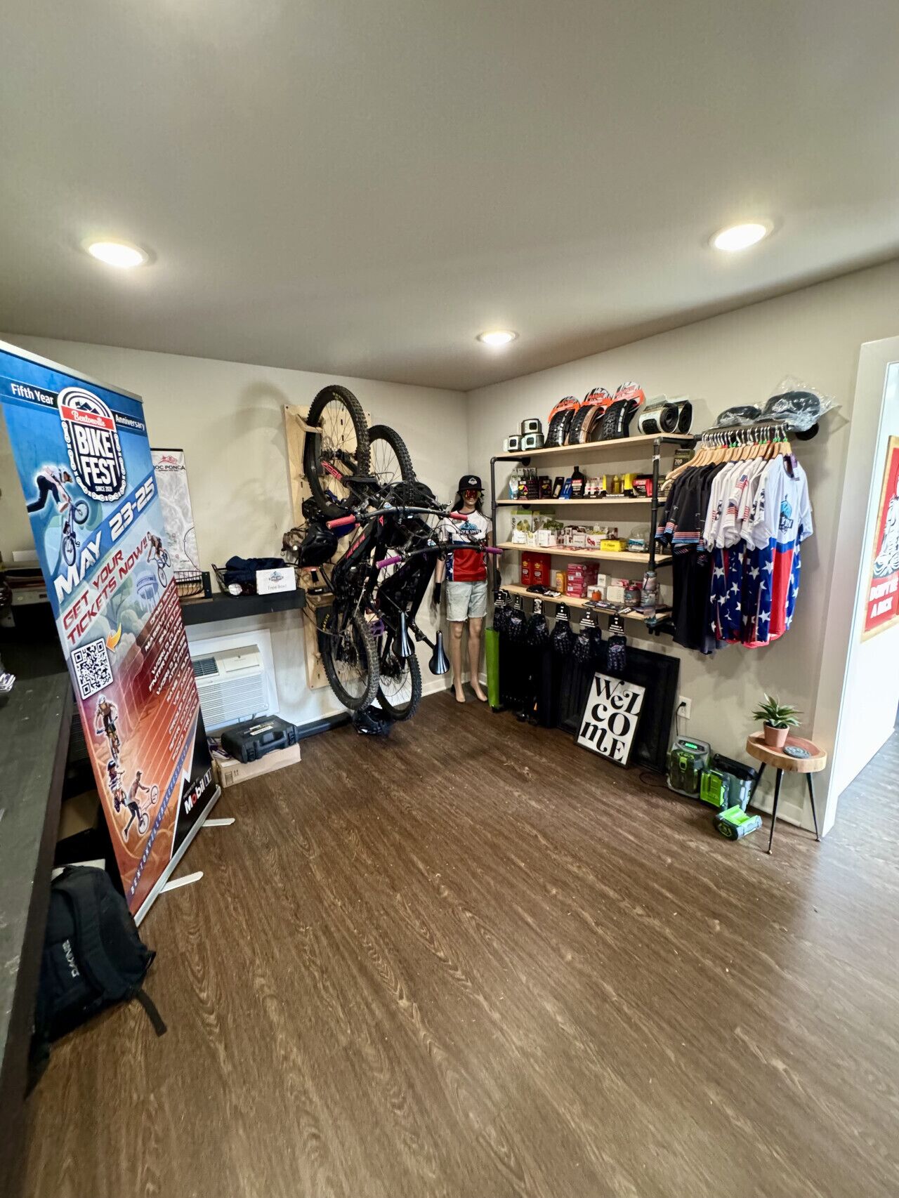 A bike shop with a wooden floor, a bike rack, and shelves with cycling gear.