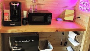 Una kitchenette equipada con cafetera, microondas, tostadora y basurero.