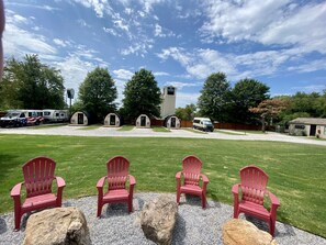 A campground with red Adirondack chairs, a gravel path, and a clear sky. - The Bike Inn #14, Buffalo River Cabin (Bentonville)