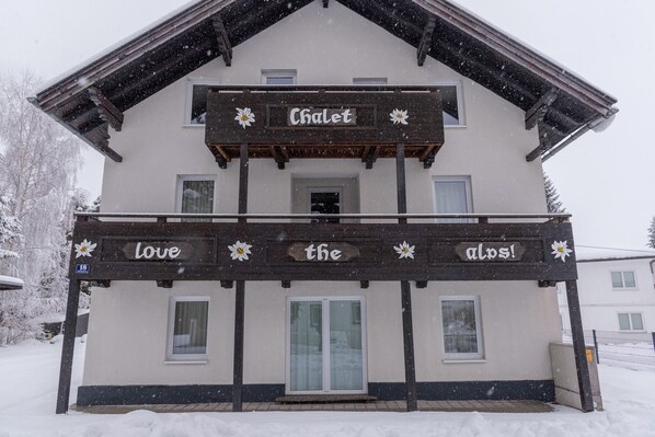Una cabaña con balcón y un cartel que dice 'Chalet Love the Alps!'