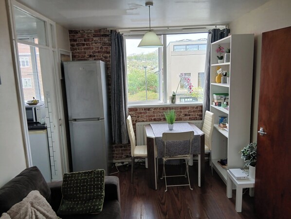 A compact kitchen with a refrigerator, dining table, and chairs. - South London 1-bed Apt, Sleeps 3, 8 Mins to Tube (London)