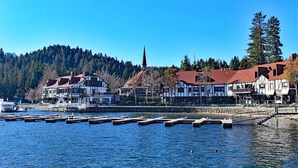 A lakeside town with traditional buildings, docks, and a forested hill in the background. - Whispering Pines | Amazing Views | Family Fun (Lake Arrowhead)