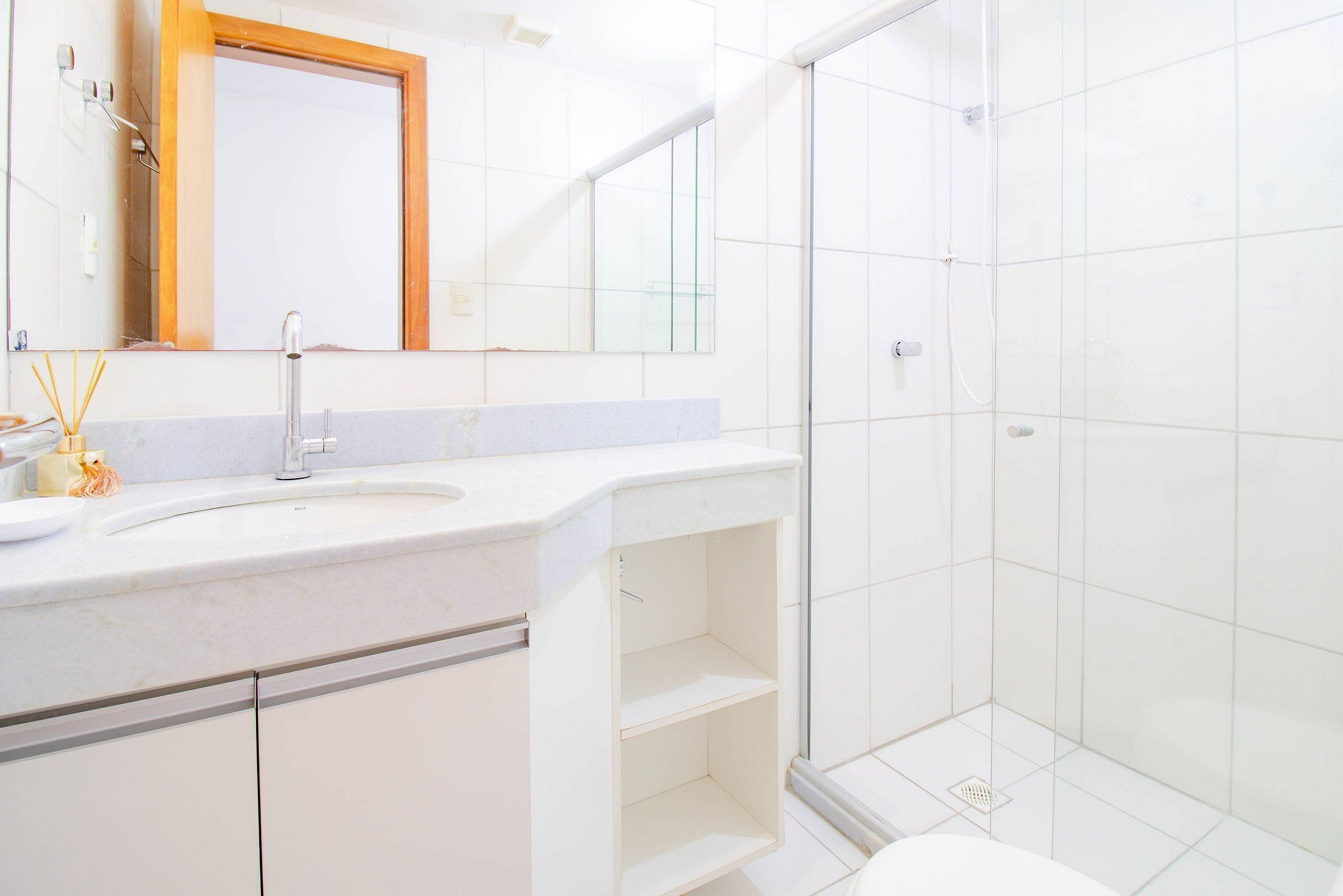 A modern bathroom with a white sink, mirror, and shower area.