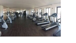 Une salle de sport équipée de plusieurs tapis de course et de plusieurs appareils elliptiques disposés en rangées.