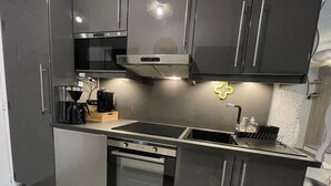 A modern kitchen with stainless steel appliances, a built-in oven, and a double sink. - Studio Calvi (Corsica) 250 meters from the beach, WiFi (Calvi)