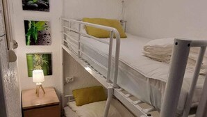 A bunk bed room with a small desk, a lamp, and a potted plant. - Studio Calvi (Corsica) 250 meters from the beach, WiFi (Calvi)