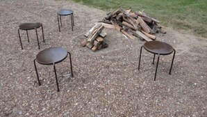 A gravel area with a pile of firewood and four metal chairs arranged around it. - Guest House with acreage to explore. (Tennyson)