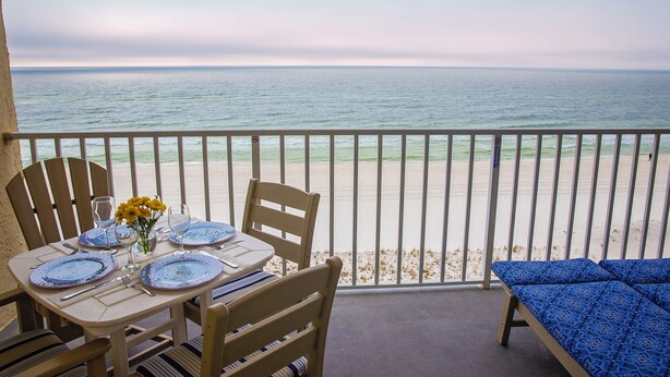 A balcony with a table set for two, overlooking a beach. - Hot Tub/Pool, Cov’d Parking (Gulf Shores)