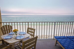 A balcony with a table set for two, overlooking a beach. - Hot Tub/Pool, Cov’d Parking (Gulf Shores)