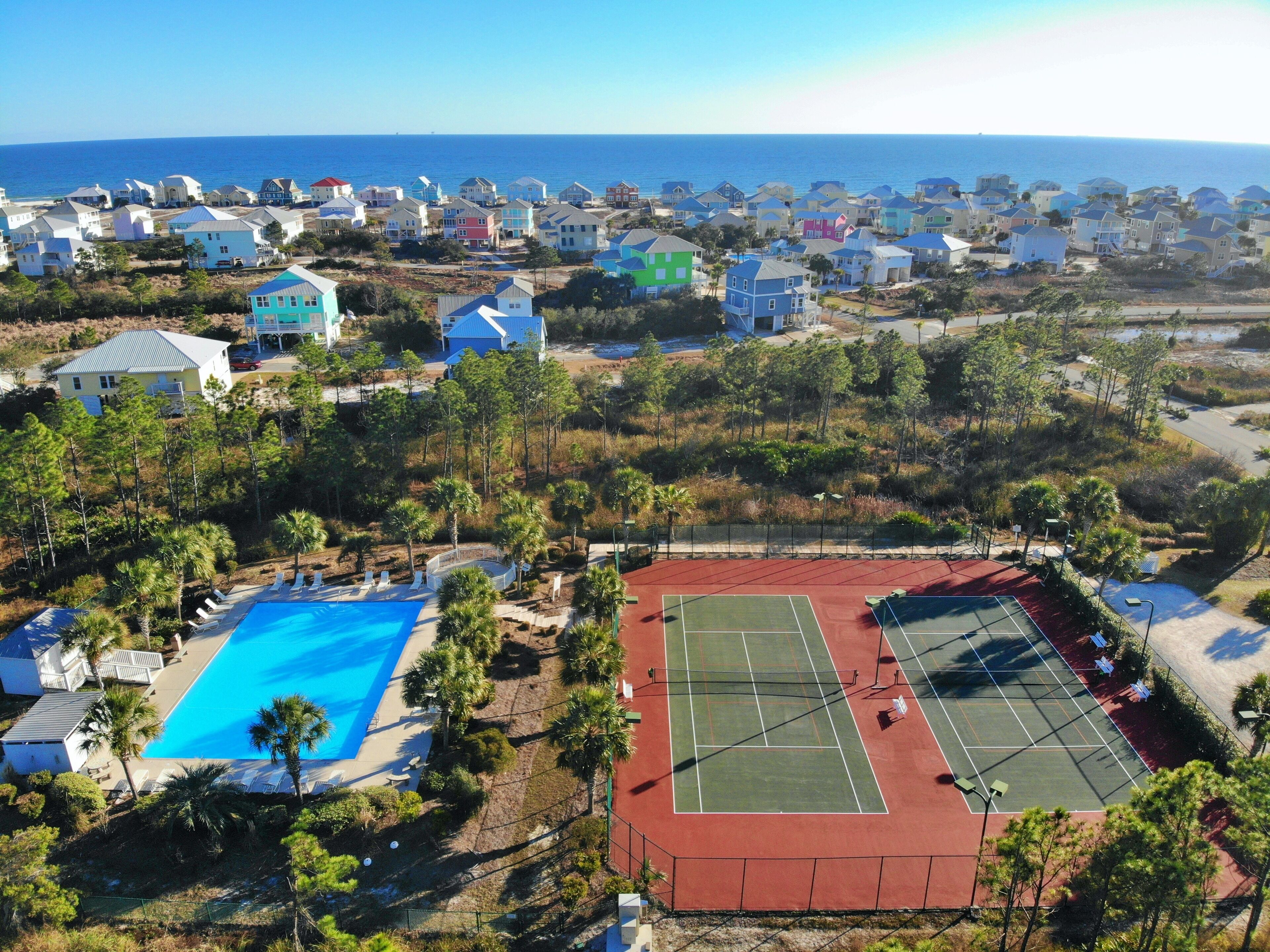 Un quartier résidentiel situé sur la côte, avec des maisons, une piscine et un court de tennis.