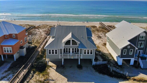 Une propriété située en bord de mer, comprenant une grande maison dotée d’un porche couvert, une plus petite maison avec un balcon et une troisième maison avec un toit en pente.