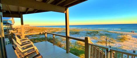 Una terraza de madera con vista a la playa y el océano.