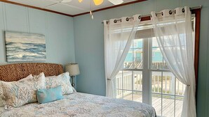 Un dormitorio con una cama grande, una lámpara, un cuadro y vistas a una terraza.
