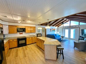 Une cuisine spacieuse avec des meubles en bois, un îlot central et un coin repas comprenant un canapé bleu et un téléviseur.