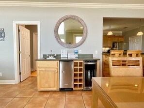 Cocina compacta con lavavajillas, fregadero y microondas. Se aprecia un armario de madera y un espejo en la pared.