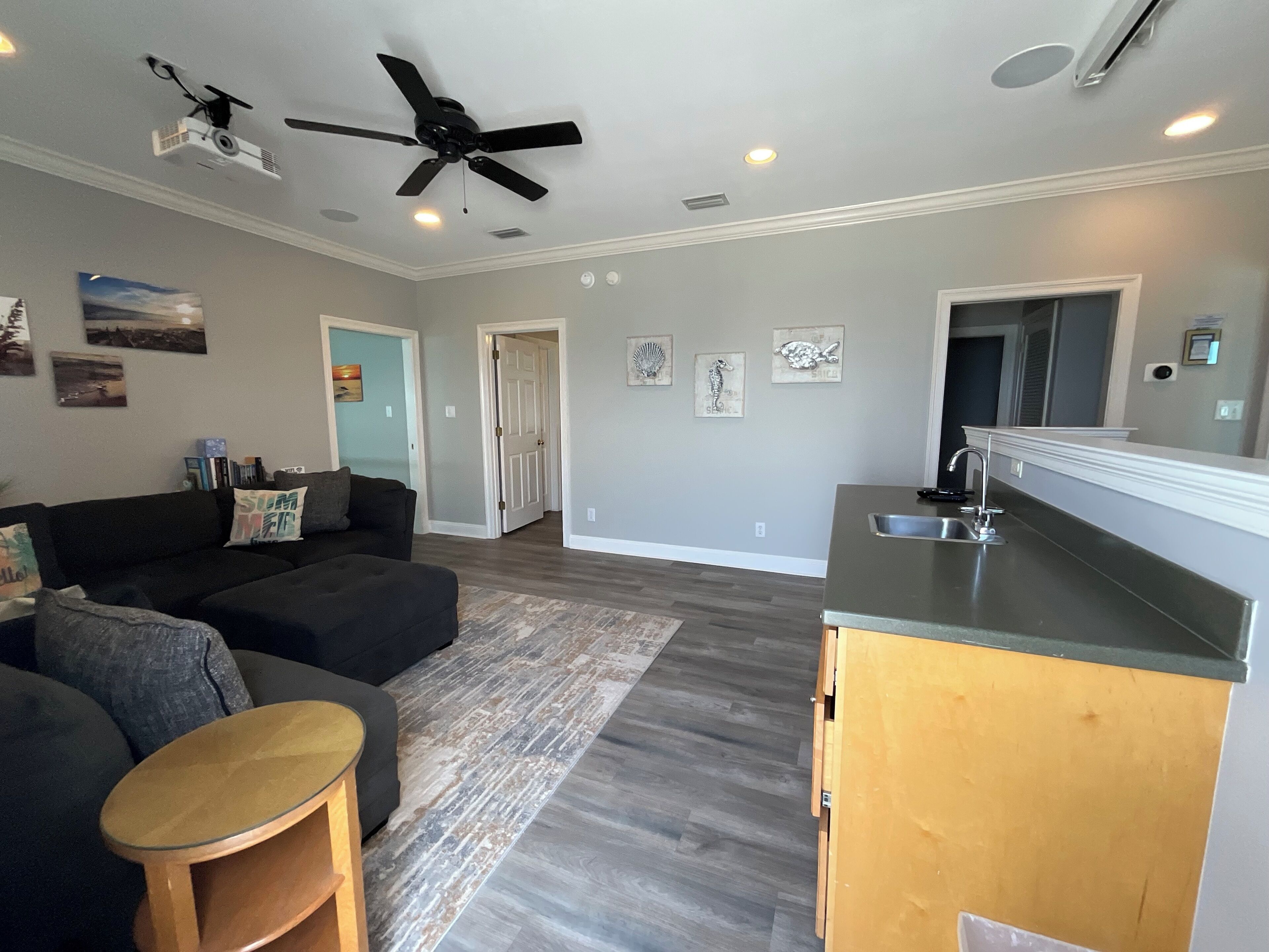A modern living room with a dark-colored sofa, a wooden coffee table, and a ceiling fan.