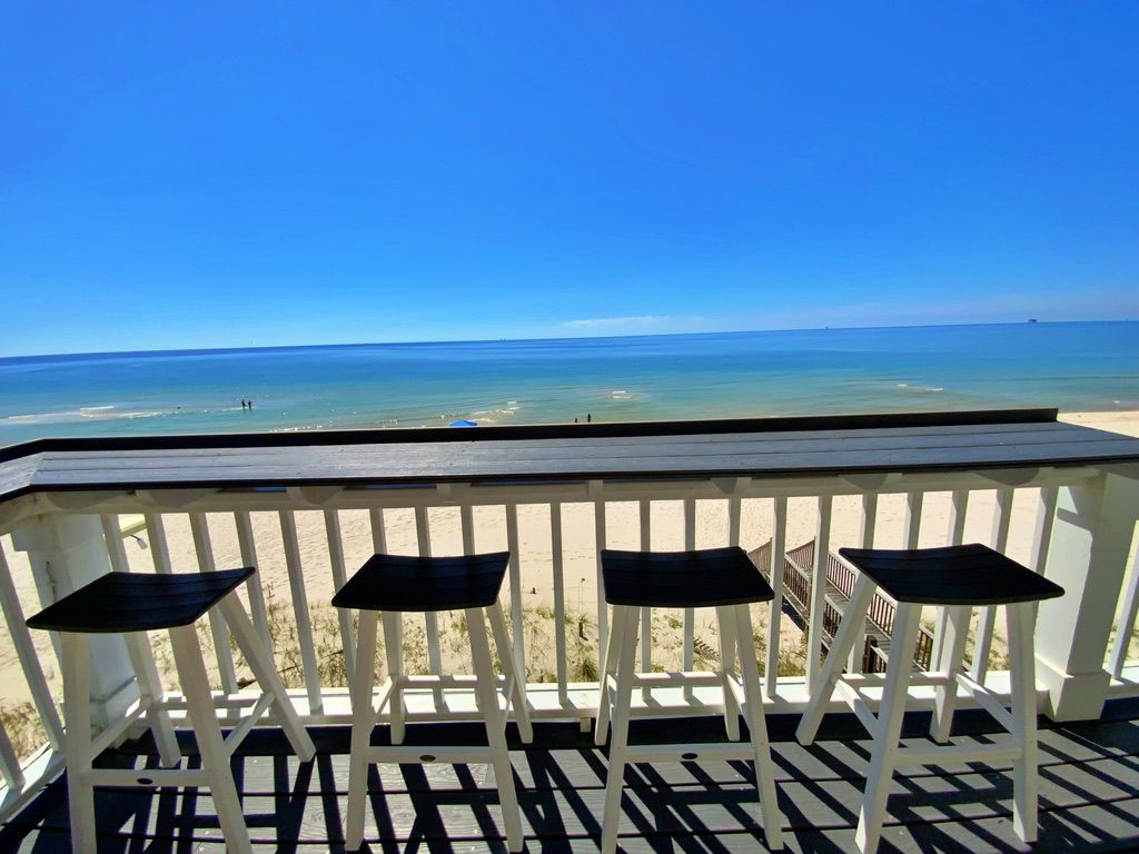 Una terraza de madera con barandilla que da a una playa.