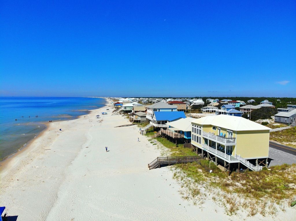 A coastal area with beach houses, a sandy beach, and a clear blue sky.