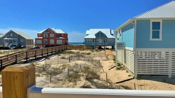 Una proprietà fronte spiaggia con diverse case, una passerella in legno e una spiaggia sabbiosa.