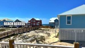 Area di accesso alla spiaggia con una passerella in legno che porta a delle case sulla spiaggia.
