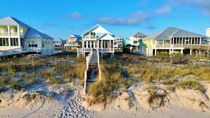 Una propiedad frente a la playa con varias casas conectadas por senderos, con terreno arenoso y vegetación escasa.