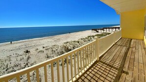 A wooden deck with a white railing overlooking a beach. - Beachfront w/ 2 living areas!  Great Location! (Gulf Shores)