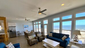 A spacious living area with a large window overlooking the ocean, a ceiling fan, and a kitchen area with a refrigerator. - Beachfront w/ 2 living areas!  Great Location! (Gulf Shores)
