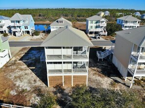 Un quartier résidentiel situé sur la côte, composé de plusieurs maisons à deux étages dotées de balcons, d’une allée en sable et offrant une vue sur l’océan.