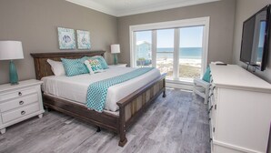 A bedroom with a bed, nightstands, a dresser, a ceiling fan, and a large window with a beach view. - Shared Private Beach Walk, Pools & Pickleball (Gulf Shores)