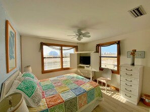 Un dormitorio con cama, escritorio, silla, cómoda y ventilador de techo.