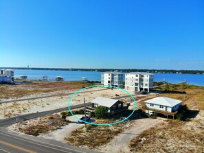 Una propiedad costera con un edificio grande, una casa más pequeña y un muelle que se adentra en el agua.