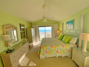 A bedroom with a bed, dresser, vanity, and a view of the ocean. - Super Cute and Beachfront! (Gulf Shores)