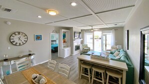 Ett rymligt vardagsrum med ett matbord, stolar, en soffa och ett kök i bakgrunden.