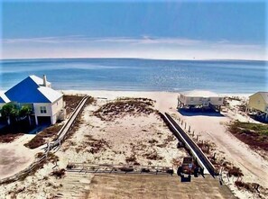 A beachside property with a paved walkway, a small building, and a house with a blue roof.