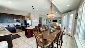 A modern kitchen with a central island, stainless steel appliances, and a dining area with a chandelier. - Easy Beach Access & Pools!  Morgantown (Gulf Shores)