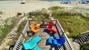 A wooden deck with colorful Adirondack chairs overlooking a beach. - Beach Front & Pet Friendly (Gulf Shores)