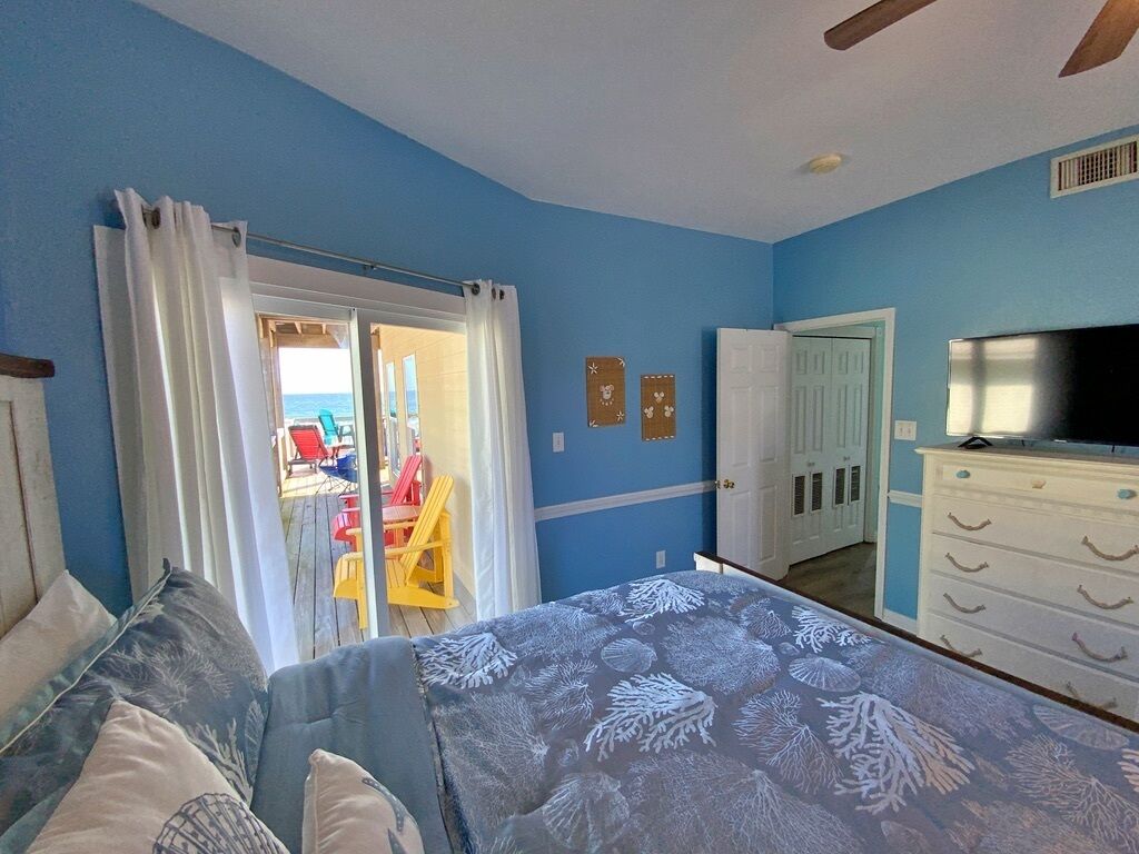 Quarto com cama, penteadeira, televisão e vista para o exterior.