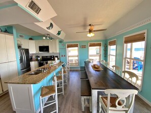 A kitchen with a central island, white cabinets, and a dining area with a long table and chairs.