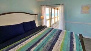 A bedroom with a bed, a view of the beach through a window, and a painting on the wall. - Beach Front & Pet Friendly (Gulf Shores)