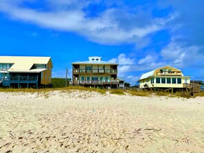 A beachfront property with multiple buildings, including a large house with a balcony and a smaller structure with a porch.